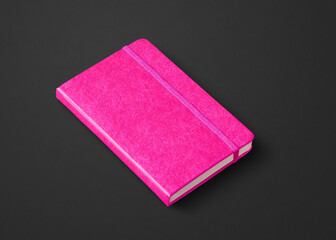 Pink closed notebook isolated on black