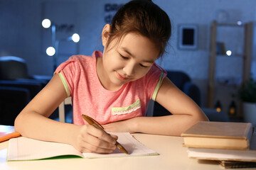 Little girl doing homework at home late in evening