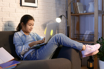 Little girl doing homework online at home late in evening