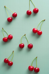 Obraz na płótnie Canvas Bright red cherry berries on pastel green background. Flat lay, top view.
