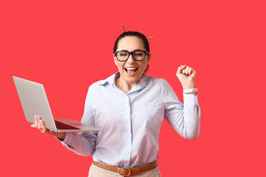 Happy female programmer with laptop on color background