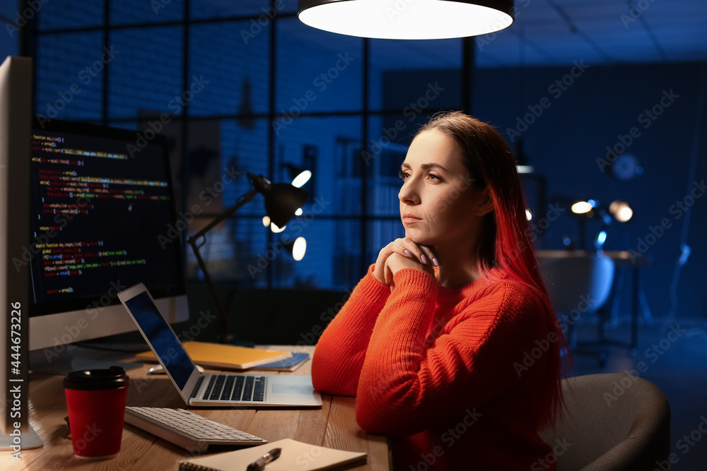 Poster female programmer working with computer in office at night