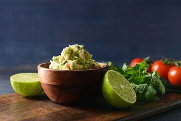 Bowl with tasty guacamole and lime on color background, closeup