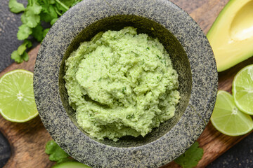 Mortar with tasty guacamole and lime, closeup