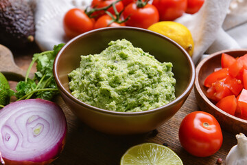 Bowl with tasty guacamole on wooden background, closeup