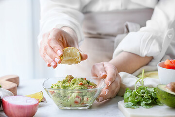 Obraz na płótnie Canvas Woman cooking tasty guacamole on table, closeup