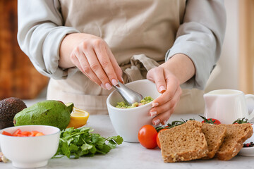 Woman cooking tasty guacamole on table