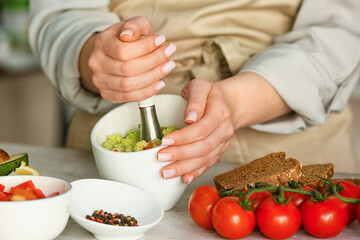 Woman cooking tasty guacamole on table, closeup