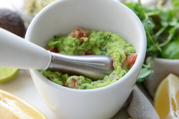 Mortar with tasty guacamole on light background, closeup