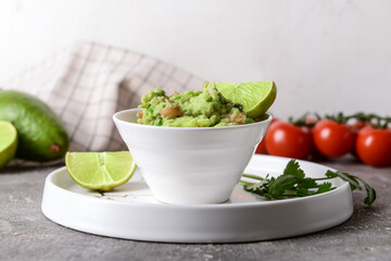 Bowl with tasty guacamole and lime on table, closeup