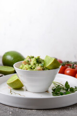 Bowl with tasty guacamole and lime on table, closeup
