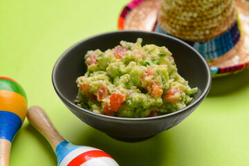 Bowl with tasty guacamole, maracas and sombrero on color background, closeup