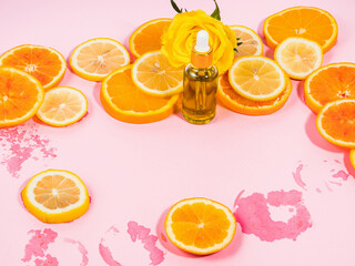 Vitamin C serum bottle with dropper on pink background with orange citrus slices