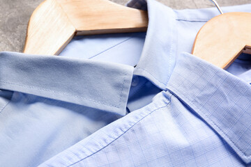 Hangers with stylish male shirts on grunge background, closeup