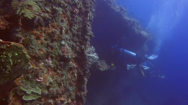 Scuba Divers swimming into a shipwreck.