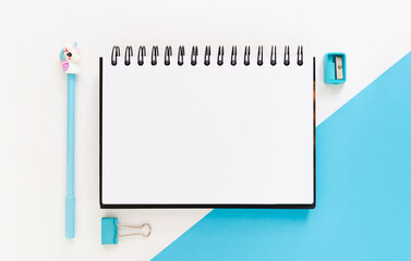 Top view of modern white blue office desktop with school supplies and stationery on table around empty space for text. Back to school concept flat lay with mockup