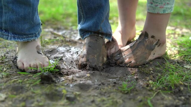 children's bare feet playing with mud on a sunny day