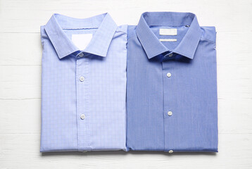 Stylish male shirts on light wooden background