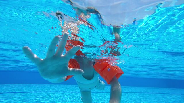The child learns to swim. Bottom view of the body of a little girl floating in the pool.
