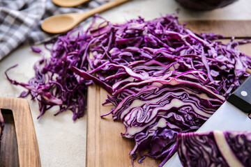 Obraz na płótnie Canvas Board with cut fresh purple cabbage on light background, closeup
