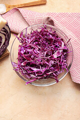 Bowl with cut fresh purple cabbage on color background
