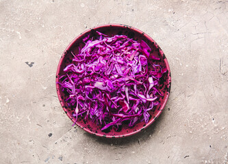 Bowl with cut fresh purple cabbage on grunge background