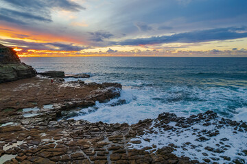 Aerial sunrise seascape with clouds and rock platform
