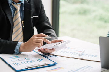 Close-up of a businessman hand holding a calculator with documents graph placed at the office desk.