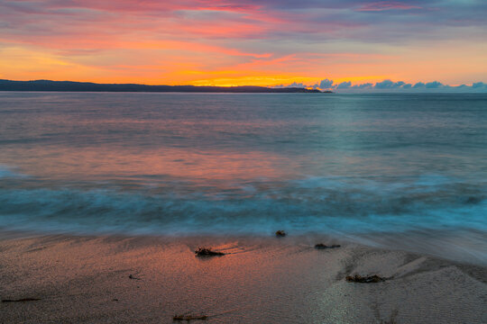 Cloud covered sunrise seascape tinged with pink
