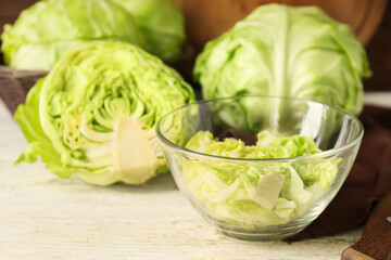 Bowl with fresh chopped cabbage on light wooden table