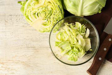 Bowl with fresh chopped cabbage on light wooden table