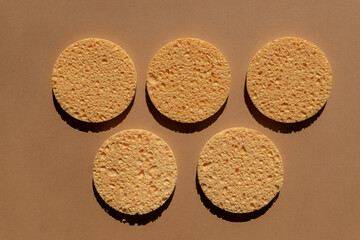set of natural round cellulose sponges for face cleansing and make up remowal on brown background