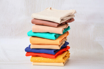 Stack of baby clothes on light background