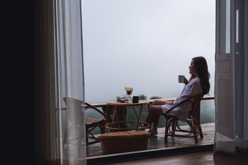 A woman drinking drip coffee and looking at a beautiful nature view on foggy day