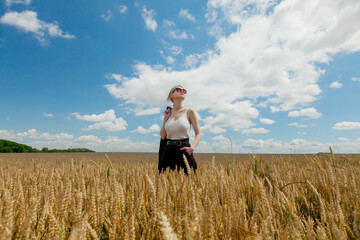 Stylish woman with blond hair posing in formal clothes in wheat field