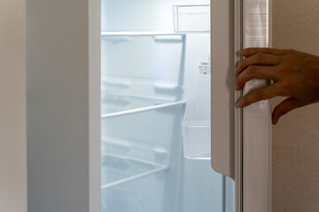 白い新品の冷蔵庫の扉を開ける男性の手