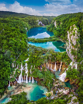 Plitvice, Croatia - Amazing view of the beautiful waterfalls of Plitvice Lakes in Plitvice National Park on a bright summer day with blue sky and clouds and green foliage and turquoise water