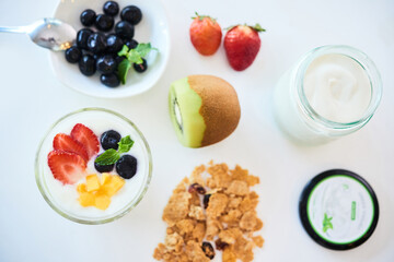 Making healthy dessert at home with granola, fresh berries and unsweetened yogurt