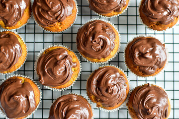 cupcakes decorated with chocolate ganache on a cooling rack 