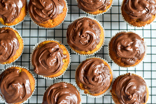 cupcakes decorated with chocolate ganache on a cooling rack 