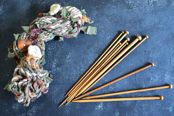 wooden knitting needles with a skein of art yarn 