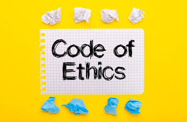 On a yellow background, white and blue crumpled pieces of paper and a notebook with the text CODE...