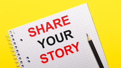 White notebook with inscription SHARE YOUR STORY written in black pencil on a bright yellow background.