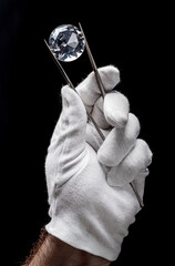 Large gemstone in jeweler's hand close up. Gem identifying and evaluating process.