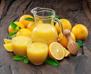 Yellow orange fruits and fresh orange juice isolated on dark wooden background.