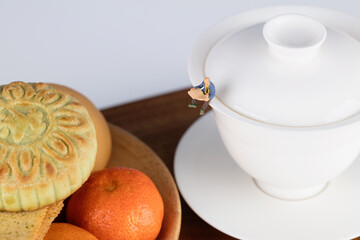 A miniature figure sitting on a tea bowl and reading a book