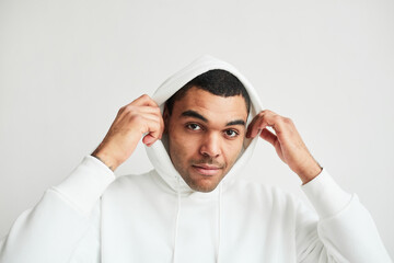 Minimal portrait of young Latin American man wearing white hoodie and looking at camera, copy space