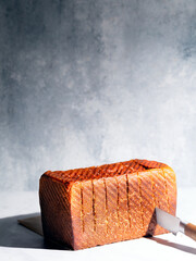 Freshly backed milk bread loaf - gray backdrop, harsh light, portrait orientation