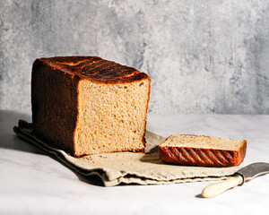 Freshly baked milk bread - sliced, harsh light photography, gray backdrop, landscape orientation