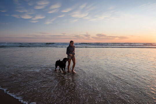 pretty young woman training her dog on the beach